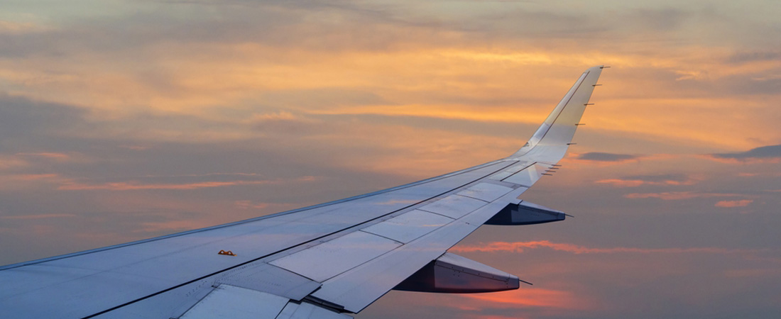 Ala de avión volando al atardecer, vista desde la cabina de pasajeros.