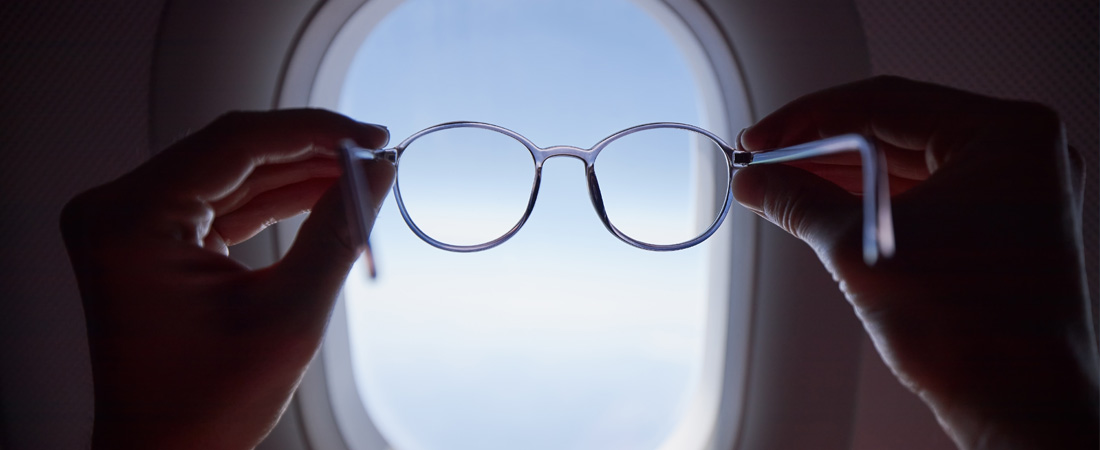 Manos sosteniendo unas gafas frente a una ventana.