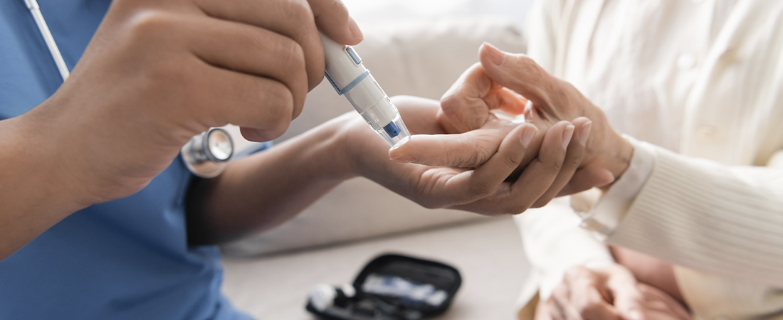 Personal sanitario realizando una prueba de glucosa en sangre o toma de muestra en el dedo de un paciente.
