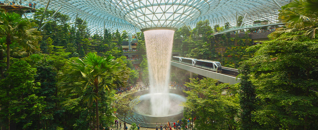 Impresionante cascada interior rodeada de vegetación en una estructura moderna de cristal.